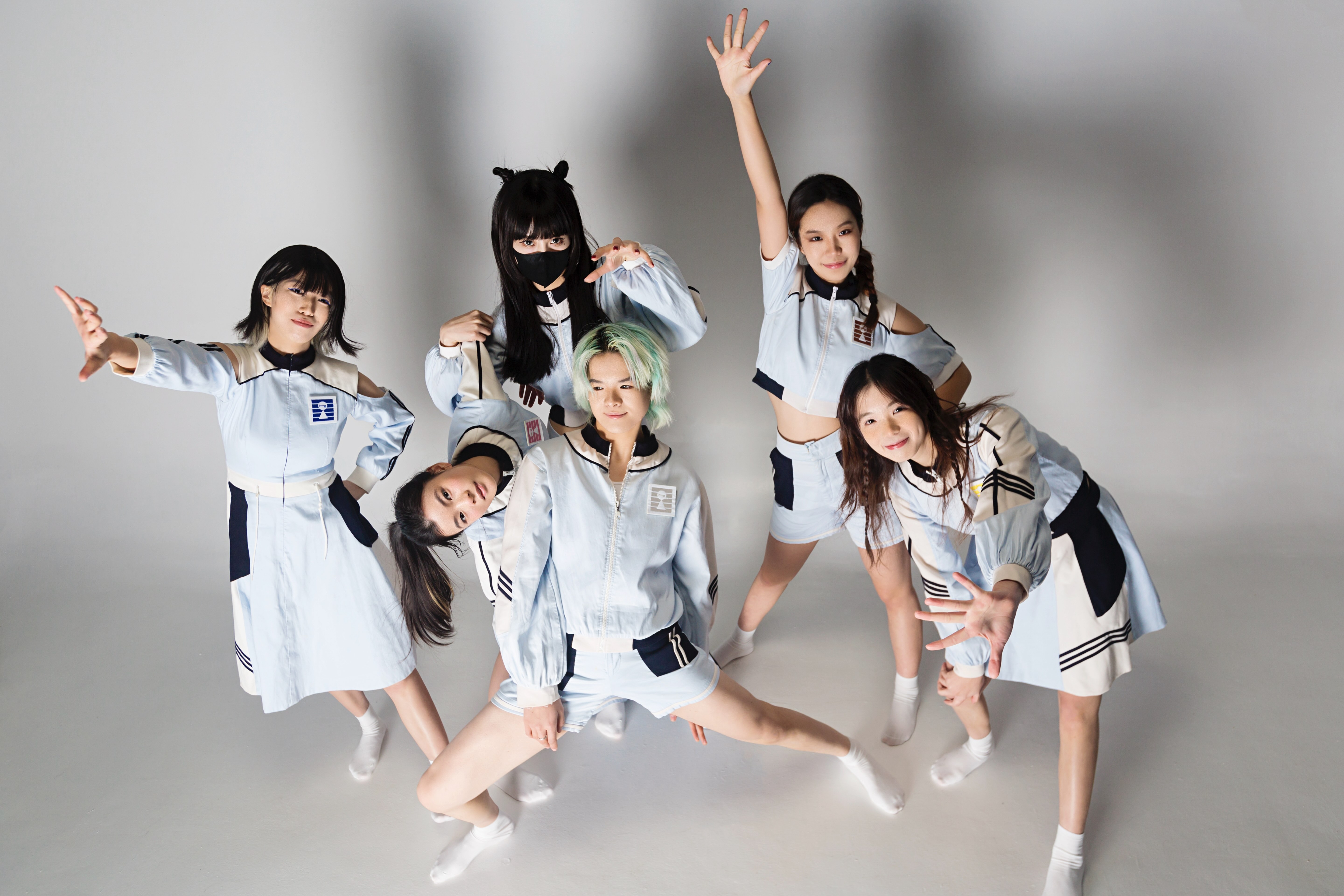 A youth pop group of six performers posing in matching light-blue outfits